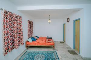 Un dormitorio con una cama naranja en una habitación blanca en Frozen Monks en Kodaikānāl