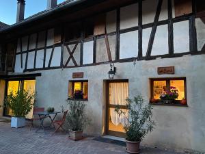 a building with windows and a table with plants at La ferme de Lili in Truchtersheim
