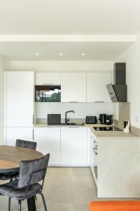 ポルト・ヴェッキオにあるFlaubert 17 - Domaine d'Arca - 4 persの白いキャビネットとテーブルと椅子のあるキッチン