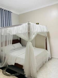 a bed with a canopy in a room at Veron’s Elegant Home in Munyonyo