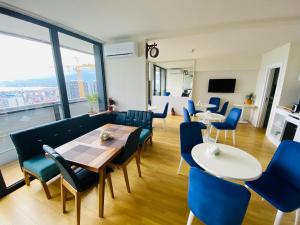 uma sala de jantar com cadeiras e mesas azuis e uma grande janela em Panorama Sea View Orbi City Aparthotel em Batumi