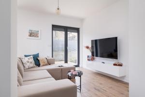 a white living room with a couch and a tv at Apartment in Krakow with parking and balcony by Renters in Modlnica