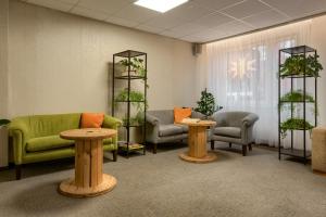 a waiting room with a green couch and two tables at Jantar Resort in Szczecin