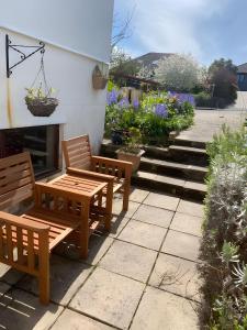 dwie drewniane ławki siedzące na patio z kwiatami w obiekcie Ferney Croft w mieście Saint Erth