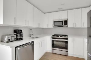 a white kitchen with white cabinets and a microwave at Jersey City 3br w elevator roof gym nr path NYC-811 in Jersey City