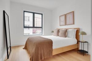a white bedroom with a bed and two windows at Jersey City 3br w elevator roof gym nr path NYC-811 in Jersey City