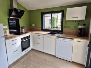 een keuken met witte apparatuur en groene muren bij Au Beau Regard in Belleu