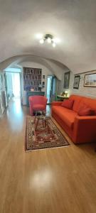 a living room with an orange couch and a red chair at Suite dei Doria in Dolceacqua