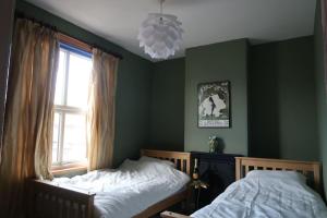 two beds in a bedroom with green walls and a window at Victorian Farrar Cottage in York