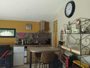 a kitchen with a table and a clock on the wall at Maisonnette en campagne au calme in Carpentras
