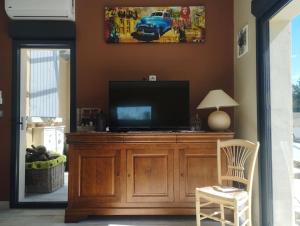 a living room with a television on a wooden entertainment center at Maisonnette en campagne au calme in Carpentras