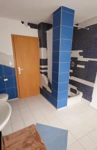 baño con lavabo y ducha con azulejos azules en Gästehaus Da Fabio, en Bad Bocklet