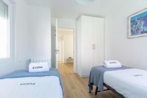 two beds in a room with white walls and wooden floors at Egona - Martinenea in Zarautz