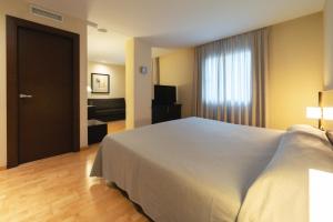 1 dormitorio con 1 cama blanca grande y TV en Port Elche en Elche