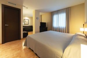 a bedroom with a large white bed and a television at Port Elche in Elche