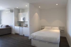 a white bedroom with a bed and a kitchen at Egona - Good Duke in Zarautz