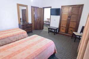 a hotel room with two beds and a flat screen tv at Los Pinos Resort & Spa Termal All Inclusive in Termas de Río Hondo