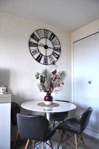 un reloj en la pared sobre una mesa con sillas en Mer et Soleil à Blonville sur mer/ Deauville, en Blonville-sur-Mer