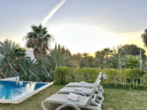 a row of lounge chairs next to a swimming pool at Gold Palm Villa in La Marsa