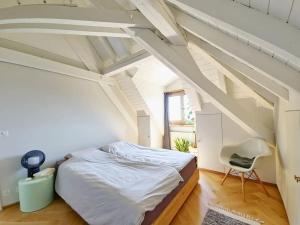 a white bedroom with a bed and a chair at Attic Apartment 2 Bedrooms in Crissier