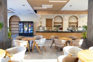 un restaurante con mesas de madera y sillas blancas en La Terrazza Hotel & Restaurant, en Hani i Elezit