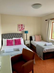 a bedroom with two beds with pink pillows and a chair at Apartment 14 in Aberystwyth