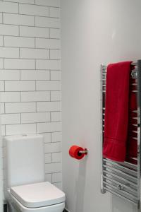 a bathroom with a white toilet and red towels at Utopian Modern Apartments in London