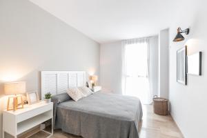 a white bedroom with a bed and a white desk at The Orbit Apartments in Barcelona