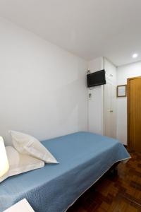Un dormitorio con una cama azul y una pared blanca en Braganca Oporto, en Oporto