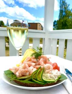 Gullringen的住宿－Gullringens Värdshus & hotell，一小盘虾和蔬菜,佐以一杯葡萄酒