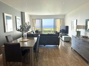 een woonkamer met een tafel, een bank en een televisie bij Surf's Up! in Newquay