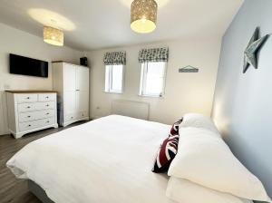 een slaapkamer met een wit bed en een televisie bij Surf's Up! in Newquay