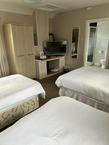 a hotel room with two beds and a flat screen tv at Rooms at the Bush in Wigton