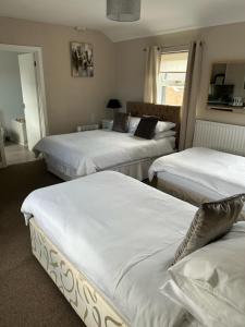 a bedroom with three beds with white sheets at Rooms at the Bush in Wigton