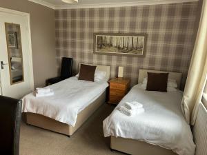 a bedroom with two beds with white sheets at Rooms at the Bush in Wigton