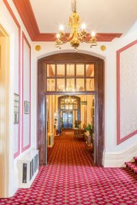 a hallway with a chandelier and a red carpet at Queens Hotel in Eastbourne