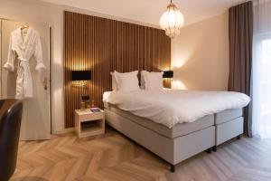 a hotel room with a bed and a robe hanging on a wall at Landhuishotel De Bloemenbeek in De Lutte