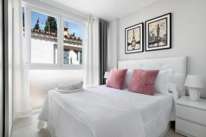 Dormitorio blanco con cama blanca y almohadas rosas en Estudio en la Carihuela, en Torremolinos