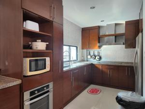 a kitchen with wooden cabinets and a microwave at 长住优惠房-芭提雅市中心高端4间卧室泳池别墅，好莱坞，21航站楼 in Pattaya Central