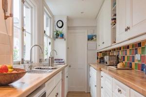 una cocina con armarios blancos y un bol de fruta en la barra en Maple Cottage, Canterbury - Little City Gem en Canterbury