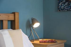 a lamp sitting on a table next to a bed at Maple Cottage, Canterbury - Little City Gem in Canterbury