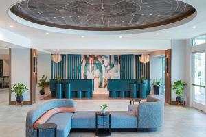 a lobby with blue couches and a circular ceiling at Hotel Landy Orlando Universal Blvd, a Tribute Portfolio Hotel in Orlando