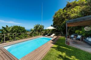 a backyard with a swimming pool and a wooden deck at The Beach Bungalow in Durban