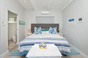 a white bedroom with a large bed with blue pillows at The Beach Bungalow in Durban