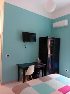 a bedroom with a bed and a desk with a television at B&B Domus Palmi in Palmi