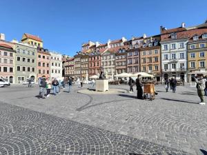 a group of people walking around a city square at SuperApart Świętojańska 19, Old Town in Warsaw
