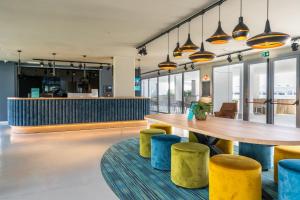 a restaurant with a wooden table and yellow stools at Student Experience Madrid Pozuelo - Luxury Hostel in Pozuelo de Alarcón