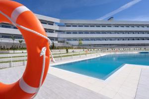 una piscina con un salvavidas naranja frente a un edificio en Student Experience Madrid Pozuelo - Luxury Hostel, en Pozuelo de Alarcón