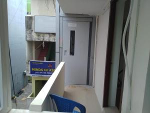 einen leeren Flur mit Tür und blauem Stuhl in der Unterkunft OGinn in Chennai