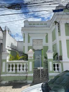 uma casa verde e branca com um portão em quintal293 no Recife